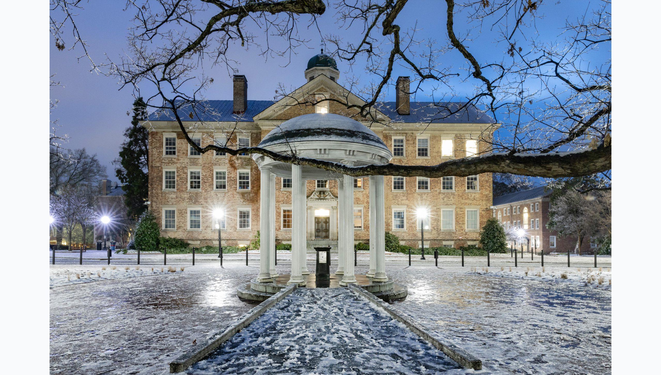 Picture of the Old Well at dawn and covered in snow and ice on the campus of U.N.C Chapel Hill. Cameron Avenue and South Building are seen in the background.